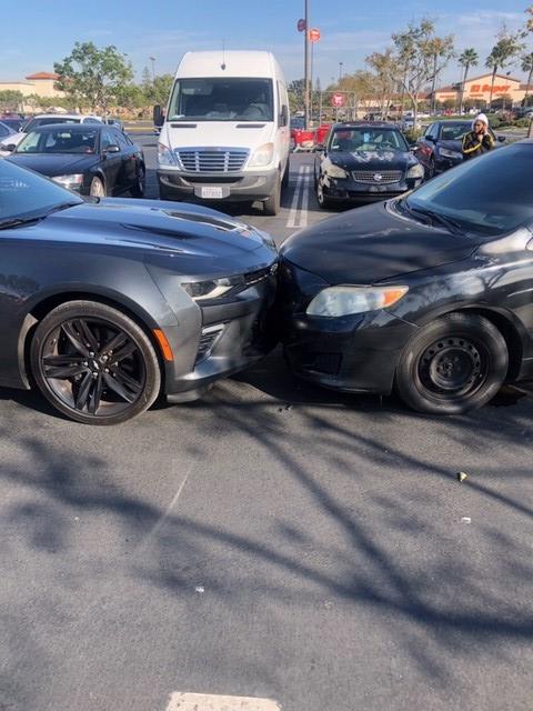 two cars shown in a head-on collision in a parking lot