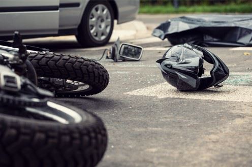 damaged motorcycle and helmet in road after crash